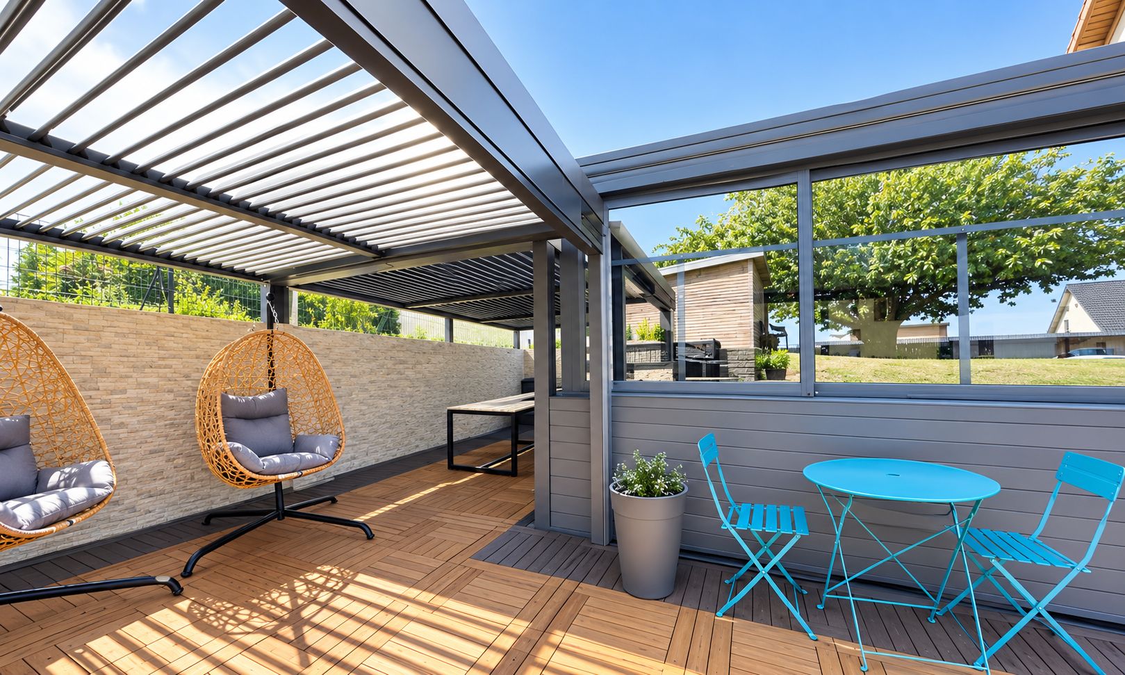 An outdoor patio with a pergola, hanging chairs, a table with chairs, and a view of the surrounding area.