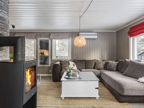 A cozy living room with a fireplace, a sofa, a coffee table, and a hanging light fixture.