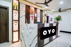 Una recepción con diseño de mármol, un ventilador de techo y un letrero que dice 'OYO'.