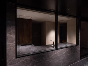 Et moderne badeværelse med et stort spejl, mørke marmorfliser og et minimalistisk design.