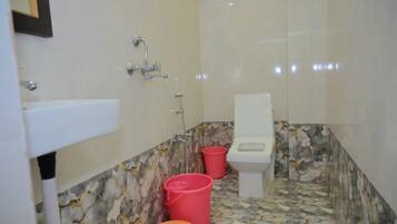 A bathroom with a toilet, sink, and two red buckets.