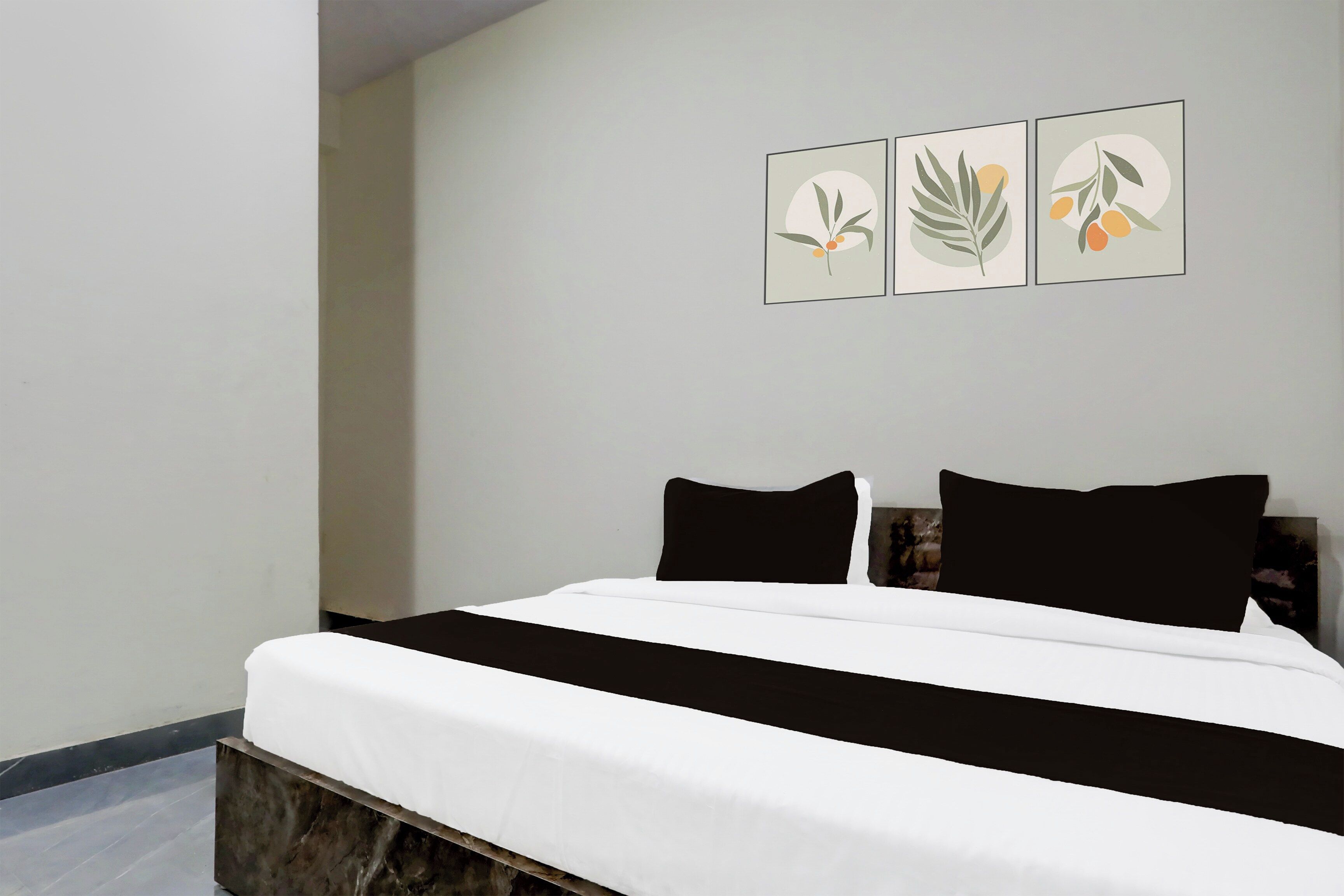 Un dormitorio con una cama, dos almohadas negras y tres obras de arte colgadas en la pared.