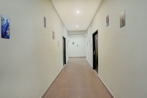 A corridor with doors on both sides, a tiled floor, and small artwork on the walls. - Hotel O Regal Garden (Faridabad)