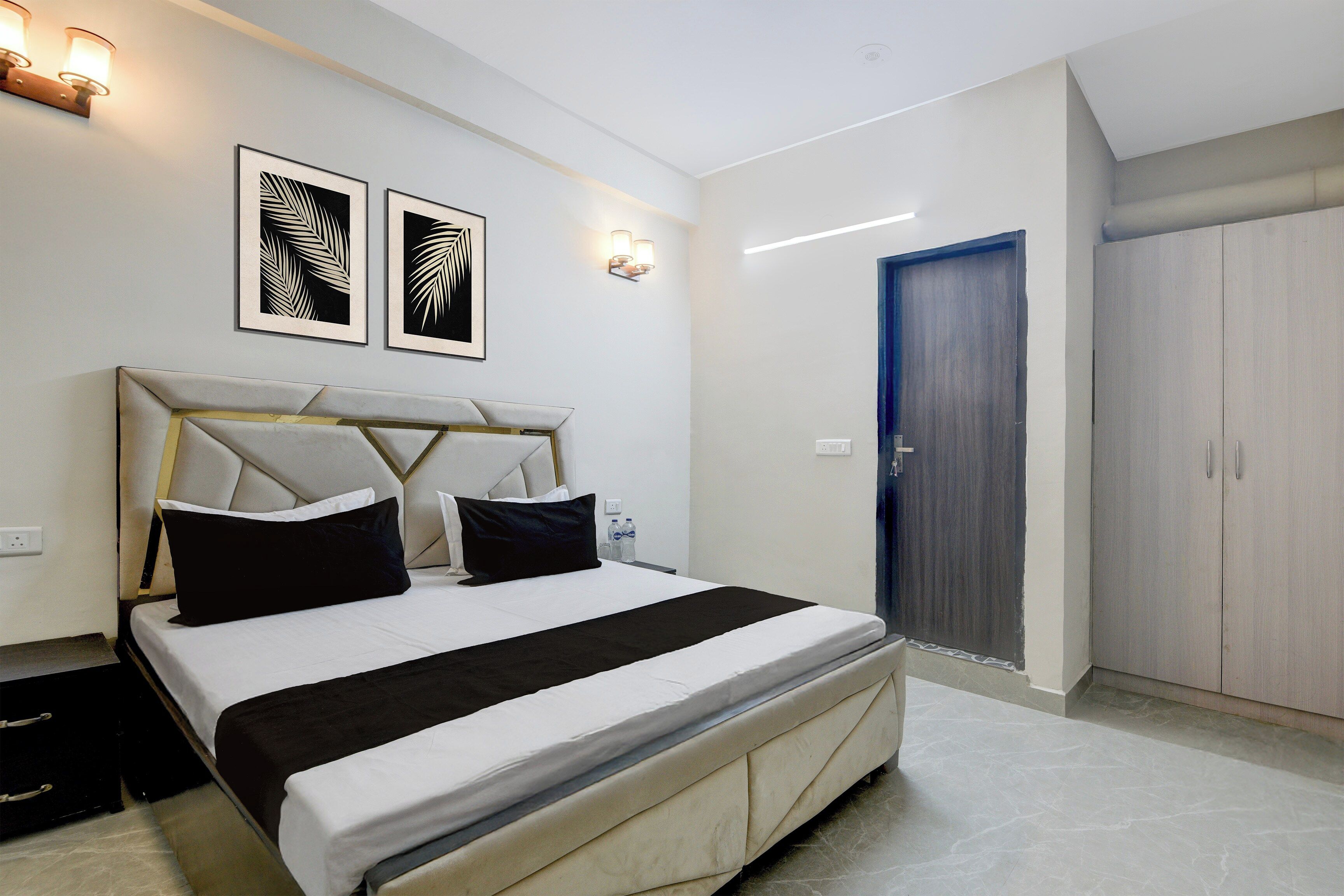 A hotel room with a bed, a wardrobe, and two wall-mounted light fixtures.
