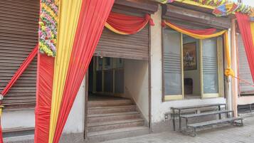 A building with a closed shutter, a staircase leading to the entrance, and a bench outside.