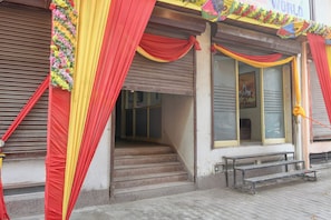 A building with a closed shutter, a staircase leading to the entrance, and a bench outside. - Hotel O Regal Garden (Faridabad)