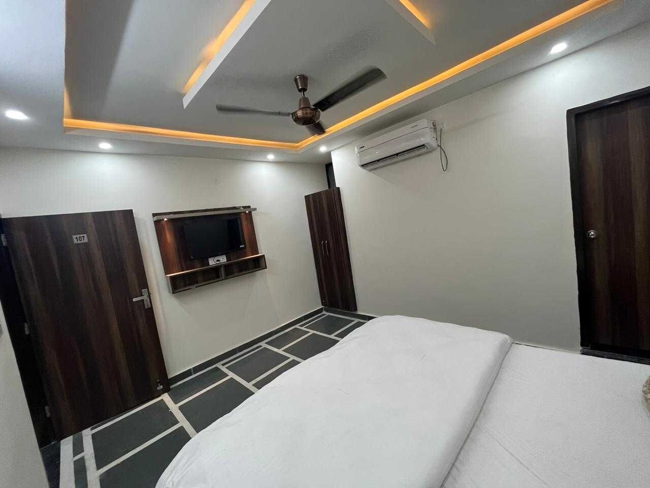 Ein Schlafzimmer mit Bett, Deckenventilator, Klimaanlage und an der Wand montiertem Fernseher.