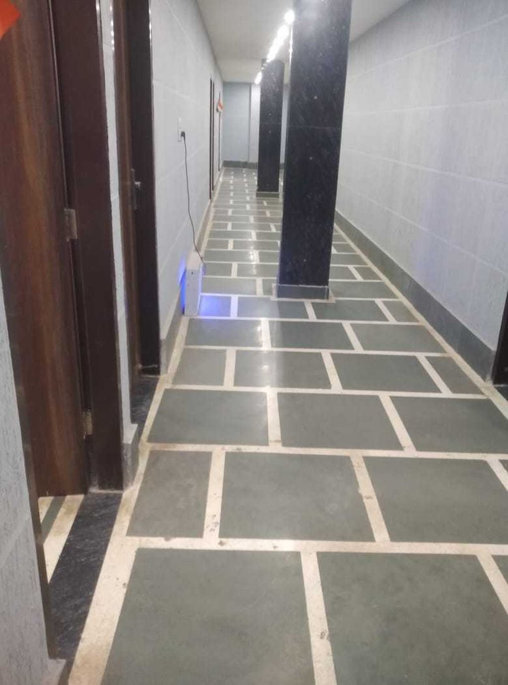 A corridor with tiled flooring and doors on the left.
