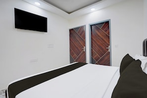 Un dormitorio con una cama, un televisor de pantalla plana montado en la pared y dos puertas con un diseño geométrico.
