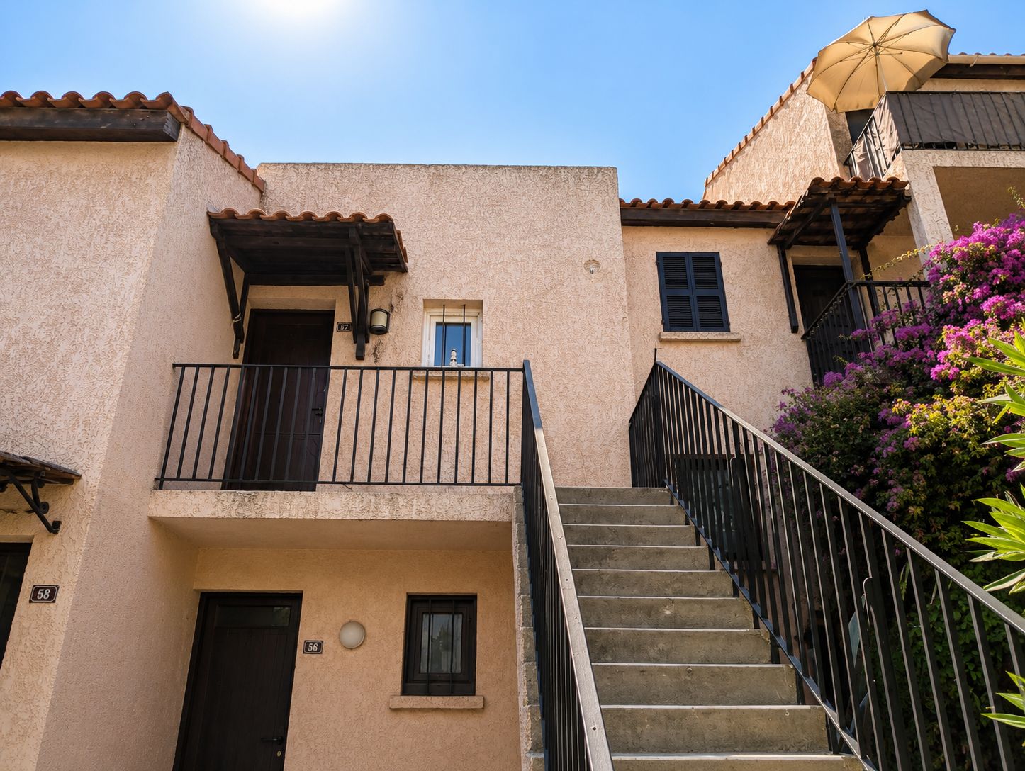 Un bâtiment doté d’un escalier menant à un balcon, d’une porte et d’une fenêtre.
