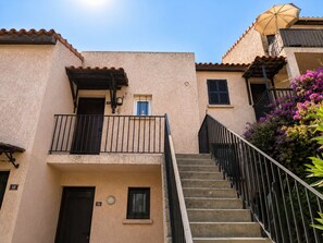 A building with a staircase leading to a balcony, a door, and a window. - New Listing (Saint-Florent)