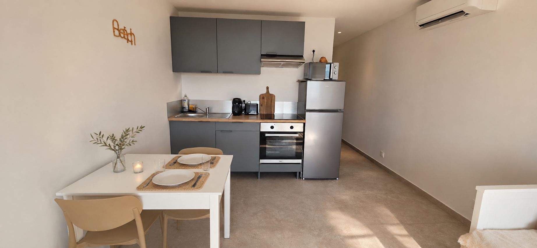 Une cuisine de taille réduite avec des meubles gris, un four encastré et un four à micro-ondes.