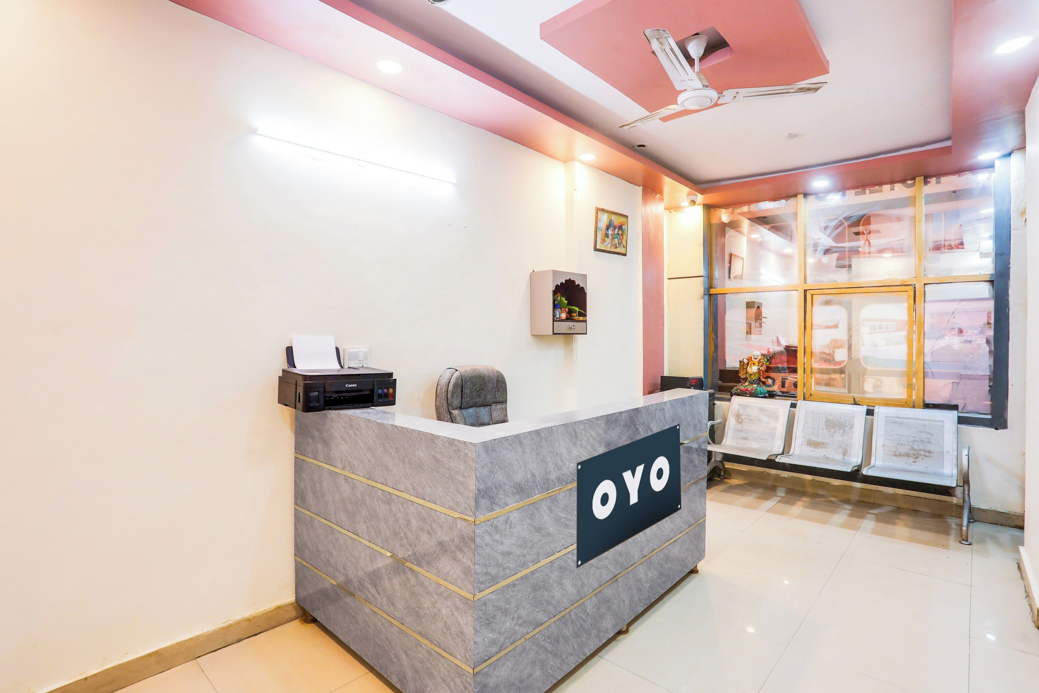 A reception desk with a sign reading 'OYO' and a seating area with chairs.
