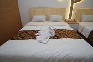 Quarto de hotel com duas camas, cabeceiras, mesas de cabeceira e uma toalha no chão.