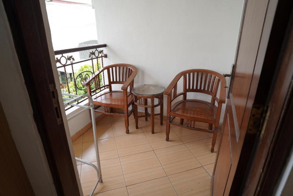 A balcony with two wooden chairs and a small round table.