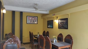Un comedor con una mesa y sillas, un ventilador de techo e iluminación en la pared.
