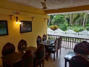 Un comedor con balcón que da a un jardín con palmeras.