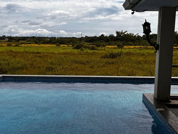 Una piscina con vista a un campo cubierto de césped y un farol.