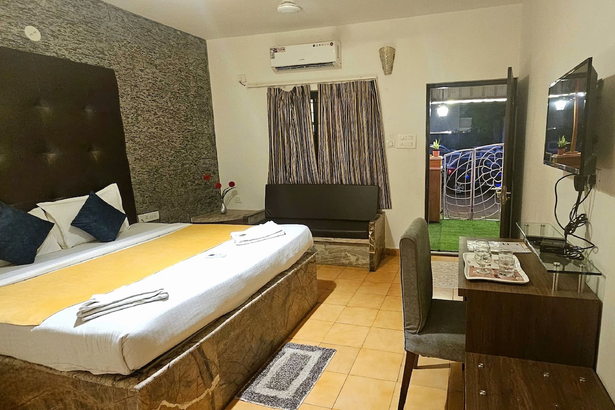 Habitación de hotel con cama, escritorio, televisor y vistas al exterior.