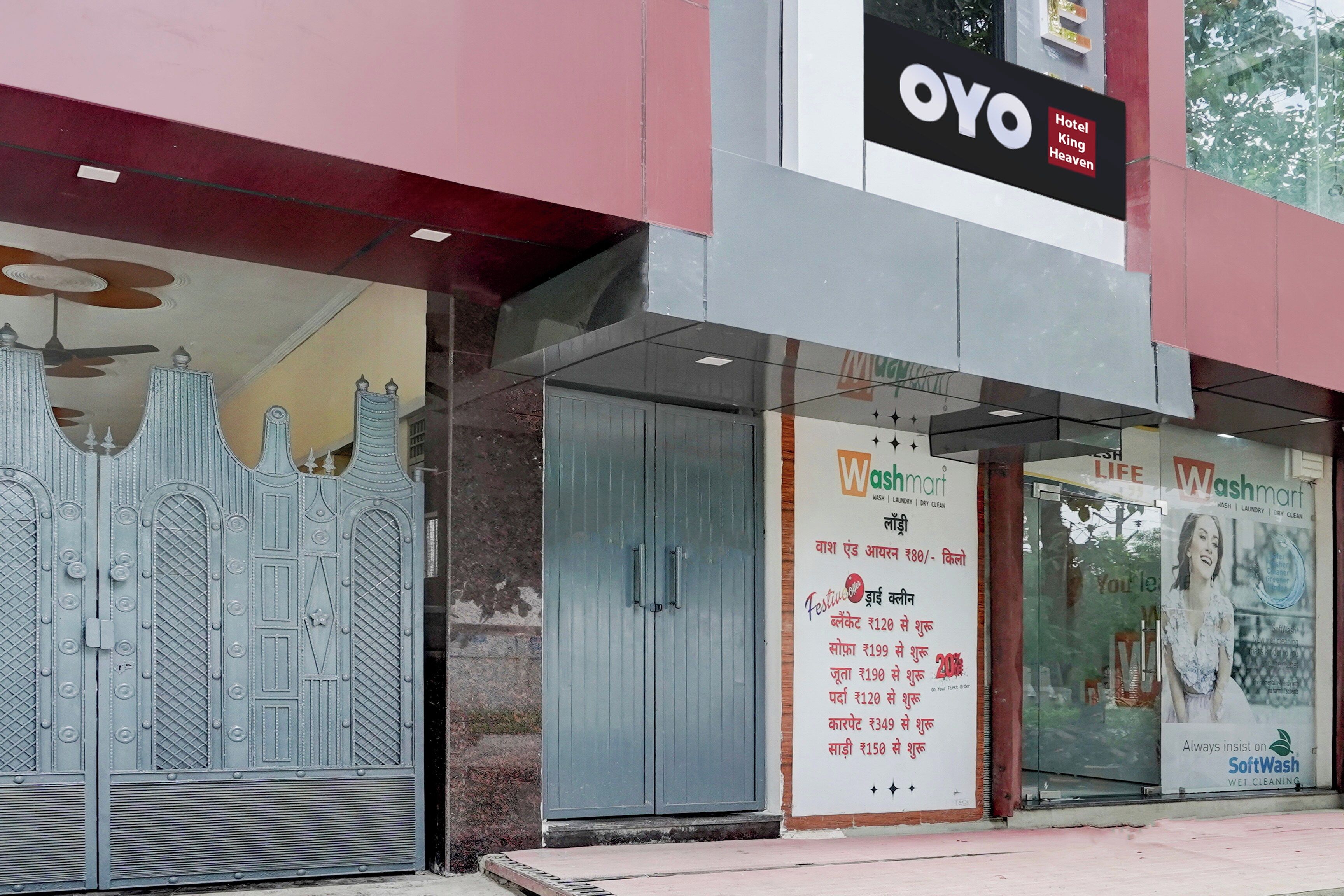 En hotelindgang med et stort skilt for OYO Hotel King Heaven, et Washmart-skilt og en plakat for SoftWash.