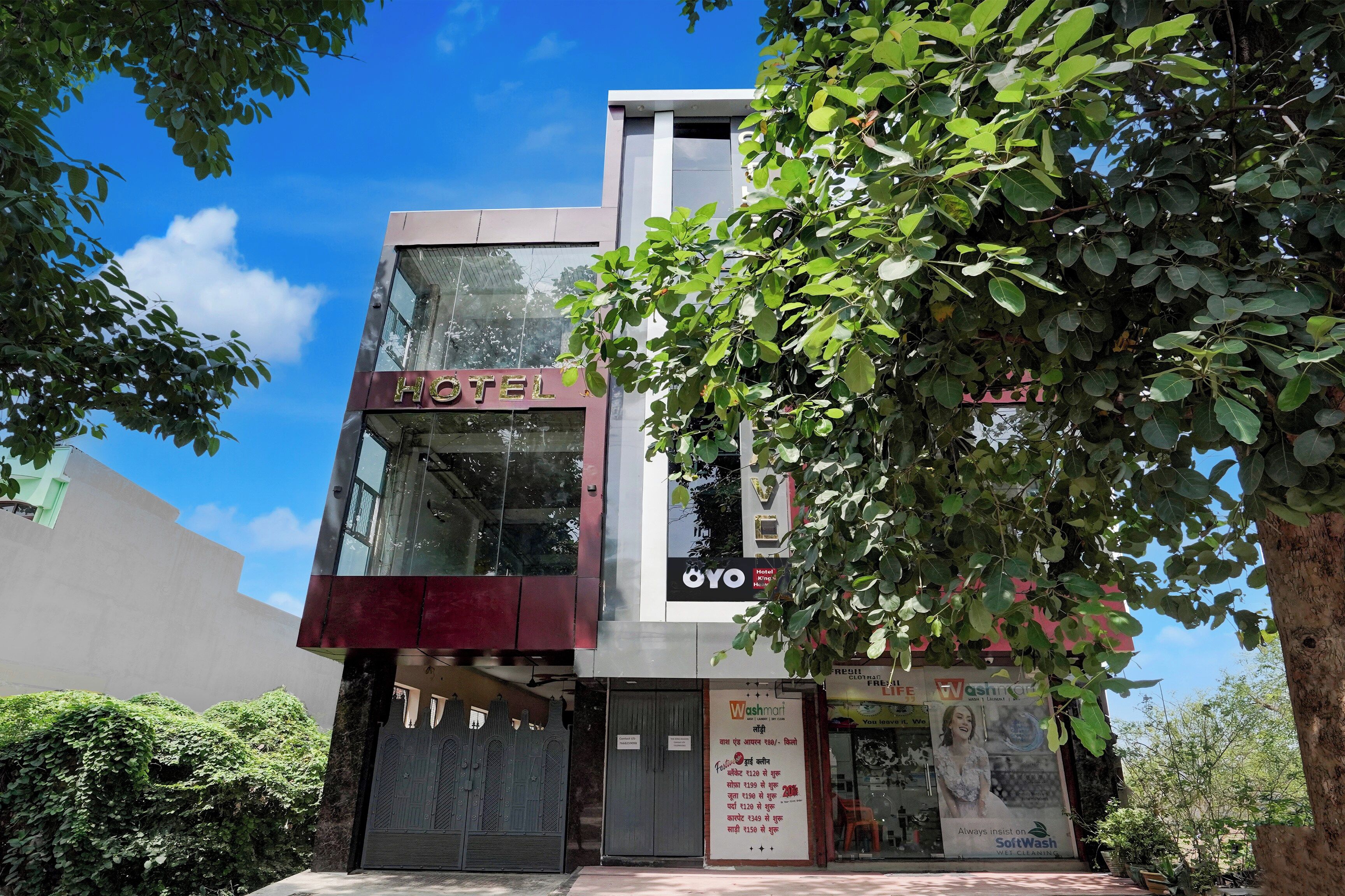 A hotel with a modern facade, a visible entrance, and a sign for a nearby shop.