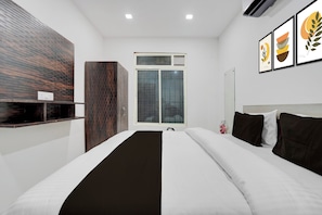 A modern hotel room with a large bed, a wooden accent wall, a window with a view of a building, and artwork on the wall. - Hotel O The King Heaven (Farrukhabad)