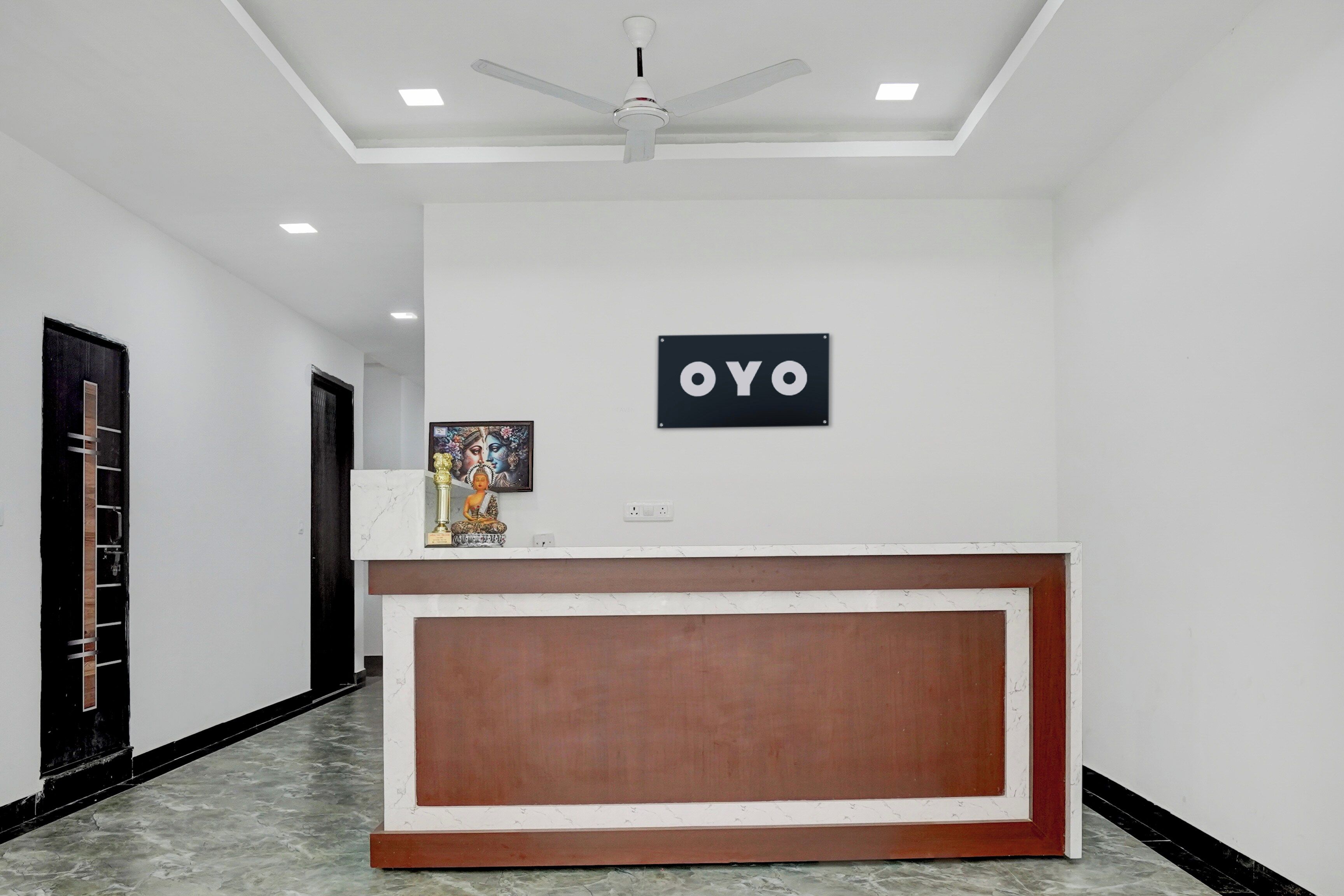 Un espace d’accueil doté d’un comptoir en marbre, d’un ventilateur de plafond et d’une enseigne indiquant « OYO ».