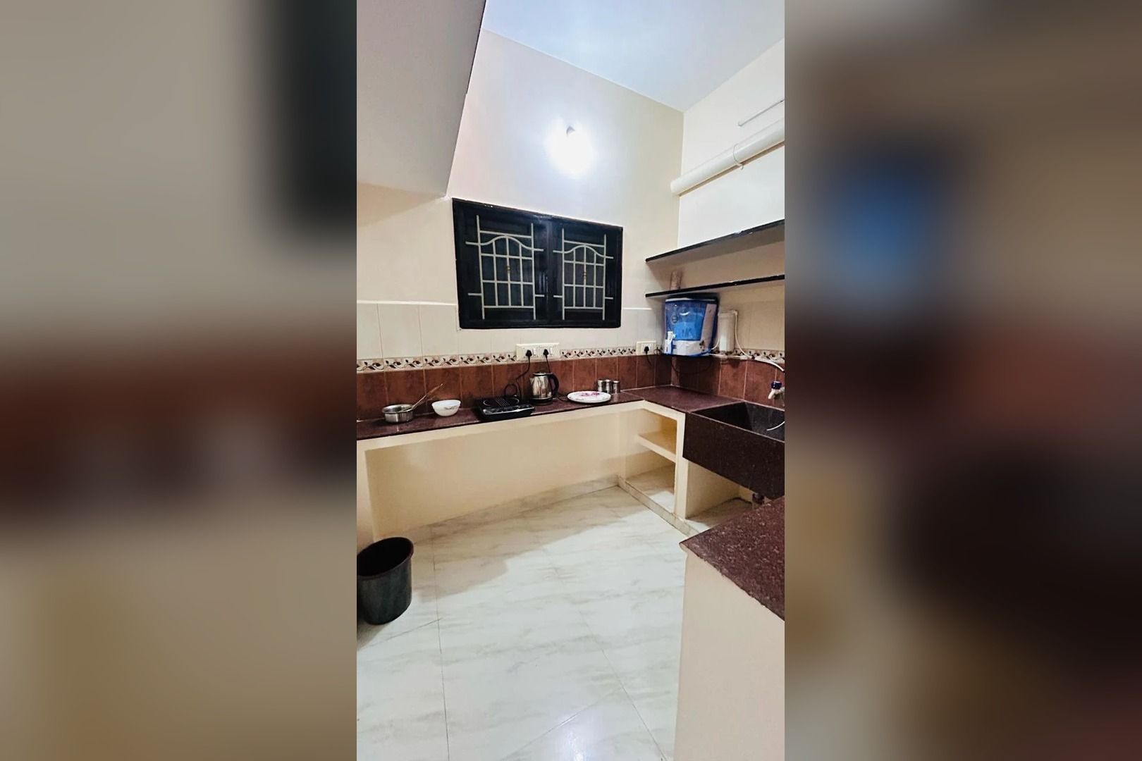 Una cucina con pavimento piastrellato, lavandino, piano di lavoro e un lampadario a parete.