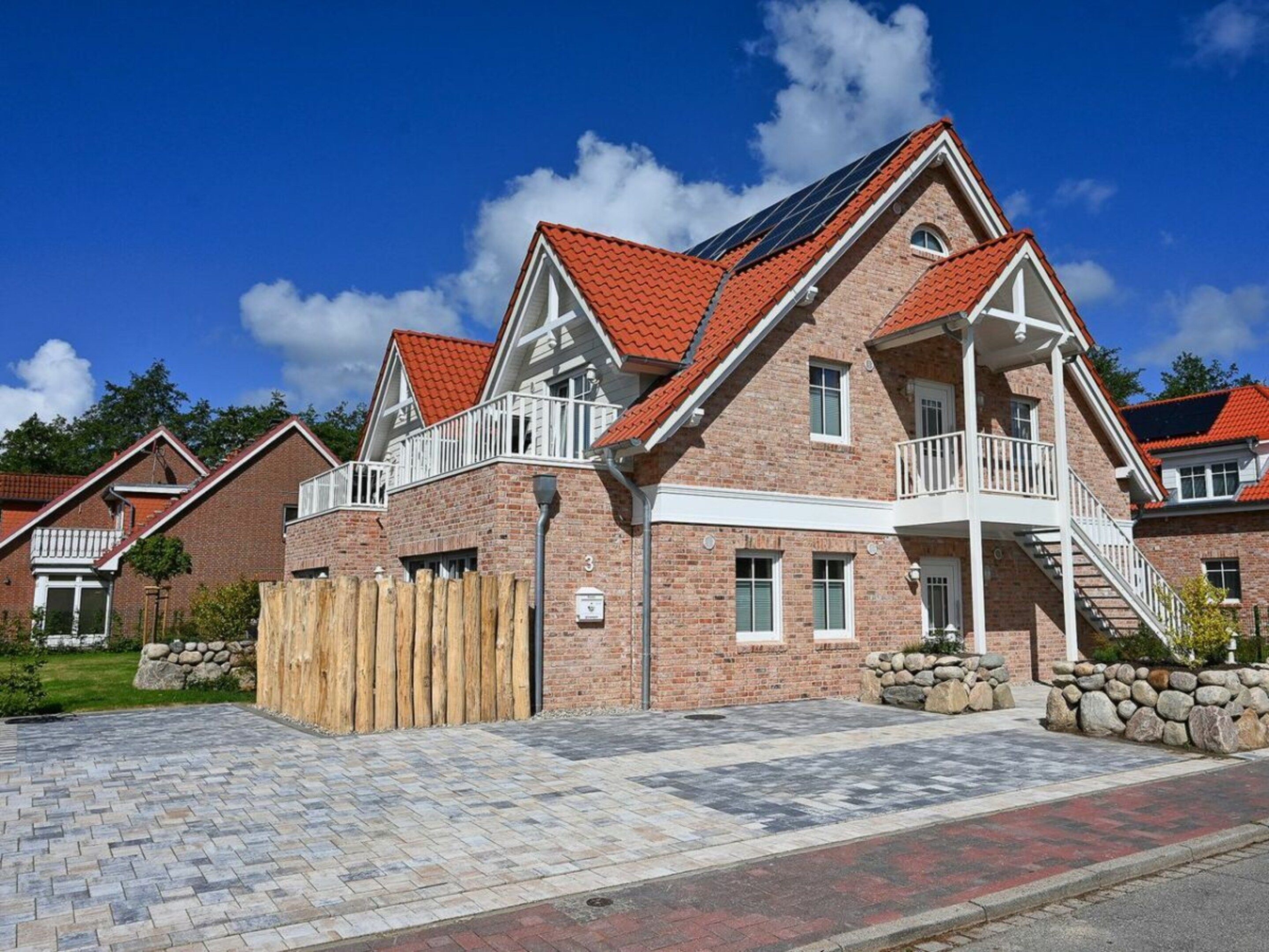 A residential building with a brick facade, red-tiled roofs, and a balcony.