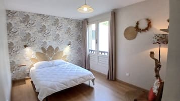 Un dormitorio con cama, ventana y pared con estampado floral.