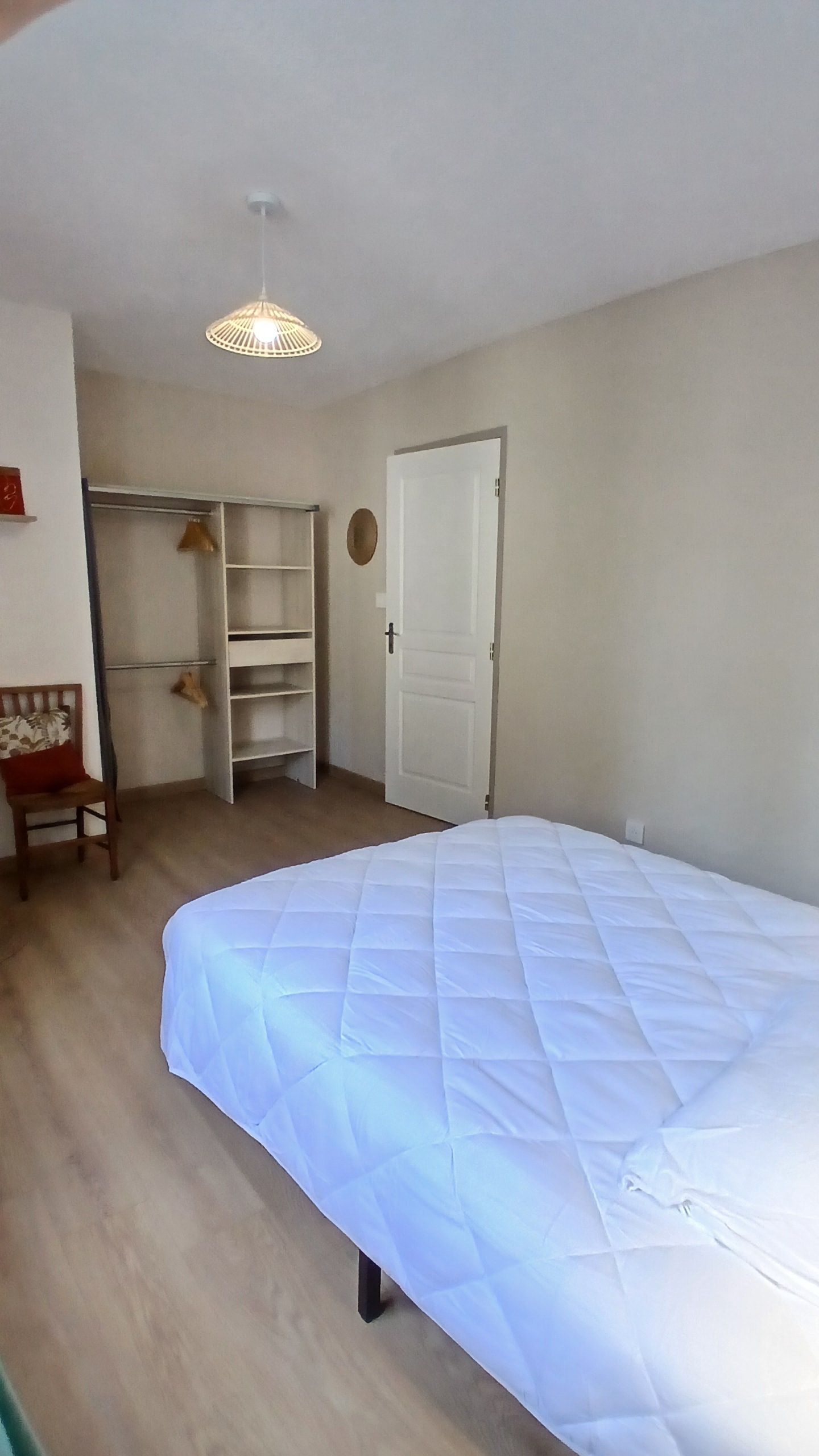Une chambre à coucher comprenant un lit, une armoire, une chaise et un luminaire suspendu.