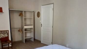 Une chambre à coucher comprenant un lit, une armoire, une chaise et un luminaire suspendu.