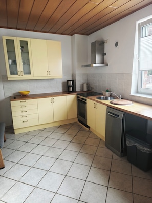 A kitchen with yellow cabinets, a dishwasher, a stove, and a window.