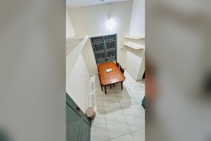 A room with a dining table, chairs, a barred window, and a tiled floor. - Private 2BHK Home with AC, Kitchen & Wi-Fi – Ramalinga Nagar, Trichy (Tiruchirappalli)