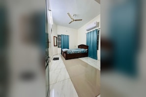 A bedroom with a bed, a ceiling fan, an air conditioner, and a window with curtains. - Private 2BHK Home with AC, Kitchen & Wi-Fi – Ramalinga Nagar, Trichy (Tiruchirappalli)