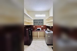 A compact kitchen with a refrigerator, microwave, and washing machine. - Private 2BHK Home with AC, Kitchen & Wi-Fi – Ramalinga Nagar, Trichy (Tiruchirappalli)