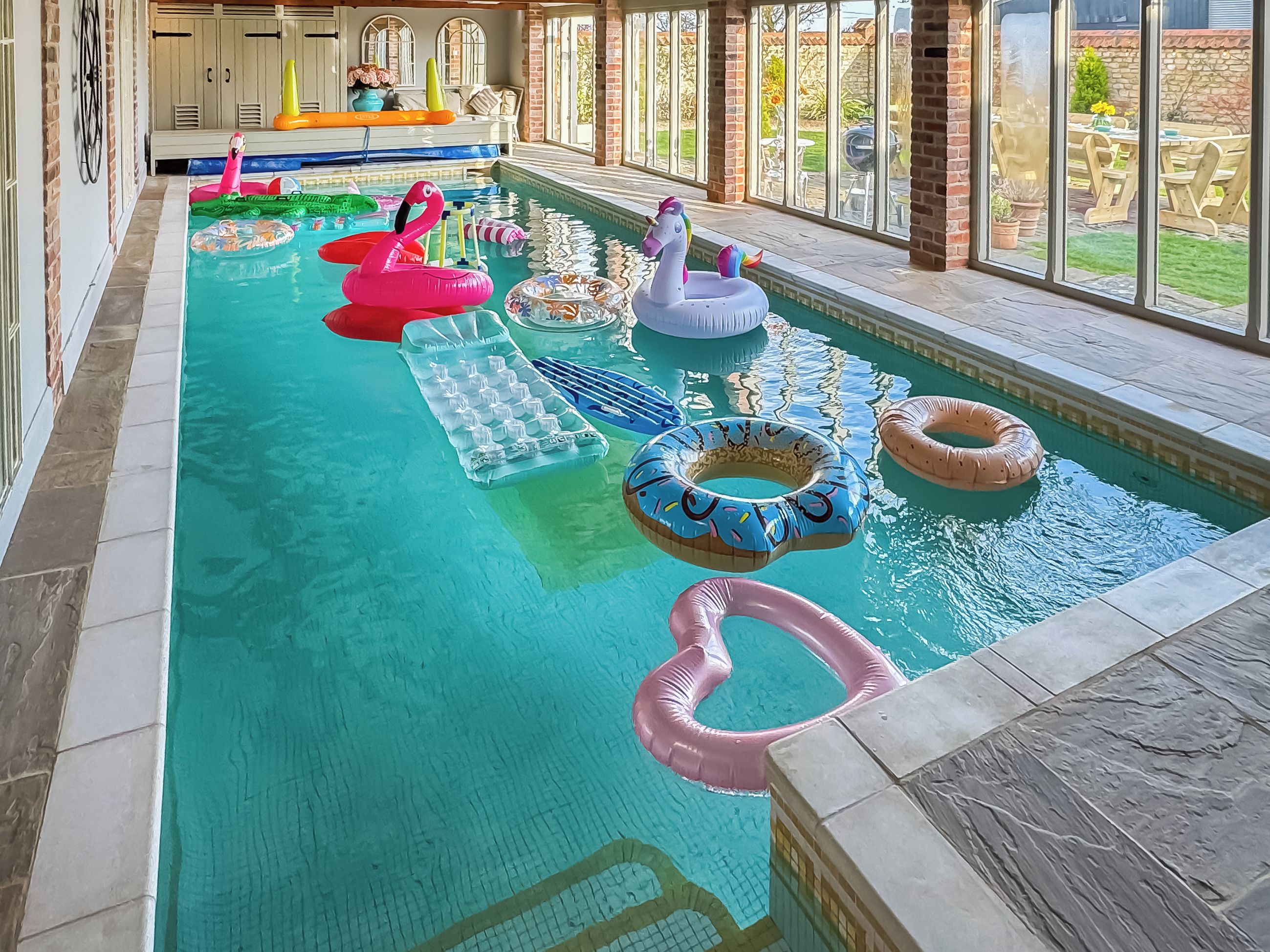 An indoor swimming pool with various inflatable toys and a clear view of the surrounding area.