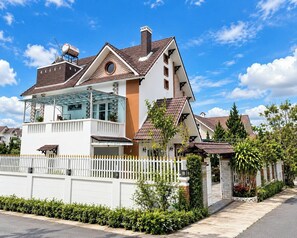 Una casa de dos pisos con balcón, garaje y patio cercado.