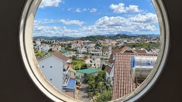 Finestra rodona amb vista a una vila, edificis i una serralada de muntanyes.