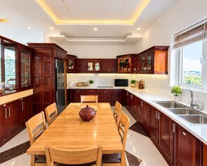 Una cocina moderna con armarios de madera oscura, una mesa de comedor de madera y un amplio ventanal.