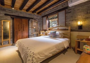 Une chambre à coucher avec un lit en bois, une armoire en bois, une fenêtre donnant sur un beau paysage et un luminaire fixé au mur.
