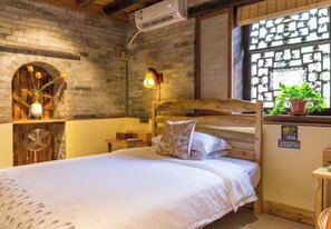 Une chambre à coucher avec un lit en bois, une table de chevet, une lampe et une fenêtre donnant sur un paysage verdoyant.