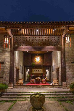 A traditional building entrance with a wooden facade, a red carpet, and a large stone lantern in the foreground. - GOVERNORS MANSION YANGSHOU (Guilin)