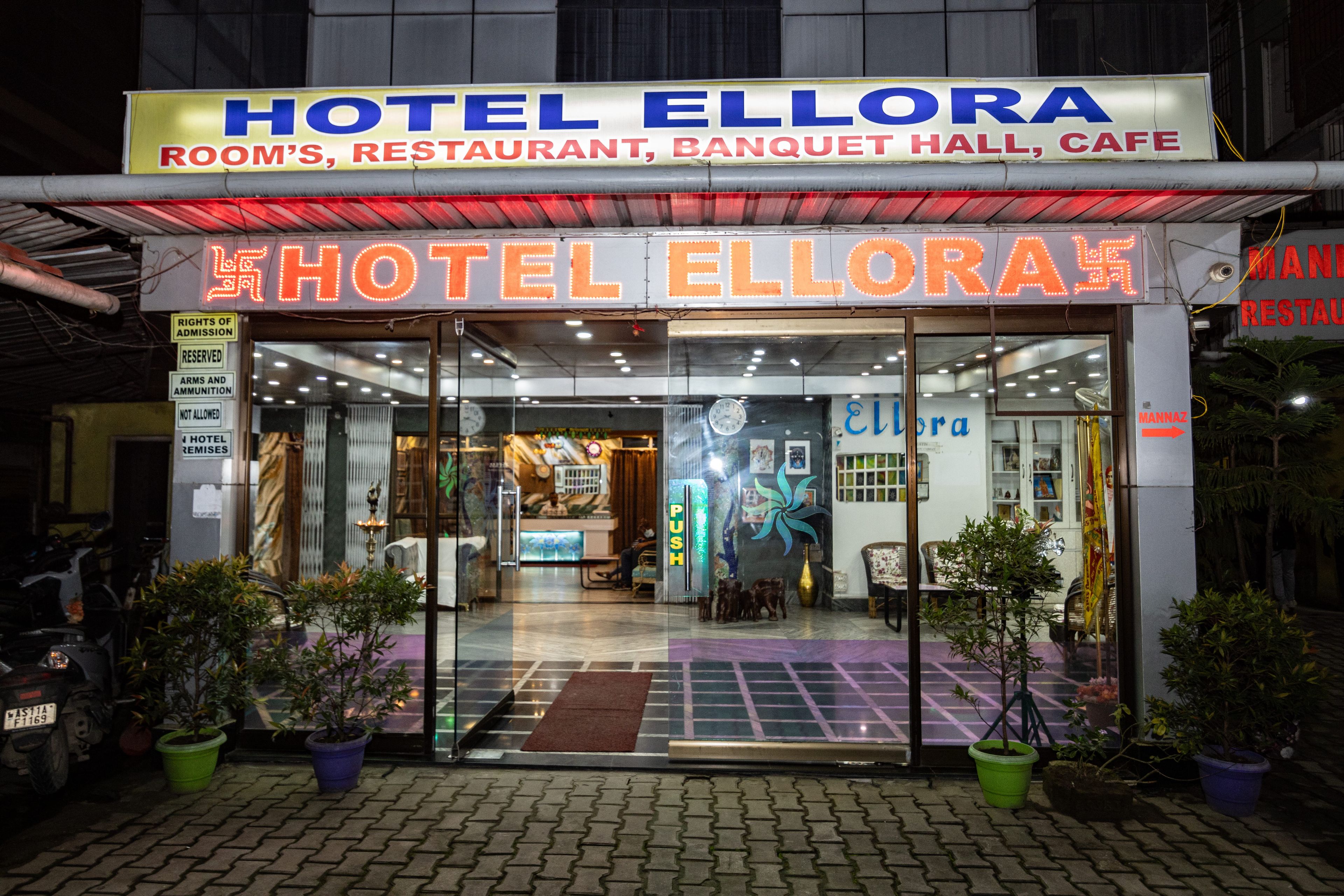 Exterior del Hotel Ellora con un letrero que indica que ofrece habitaciones, un restaurante, un salón de banquetes y una cafetería.