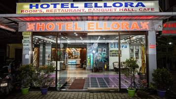 Exterior del Hotel Ellora con un letrero que indica que ofrece habitaciones, un restaurante, un salón de banquetes y una cafetería.