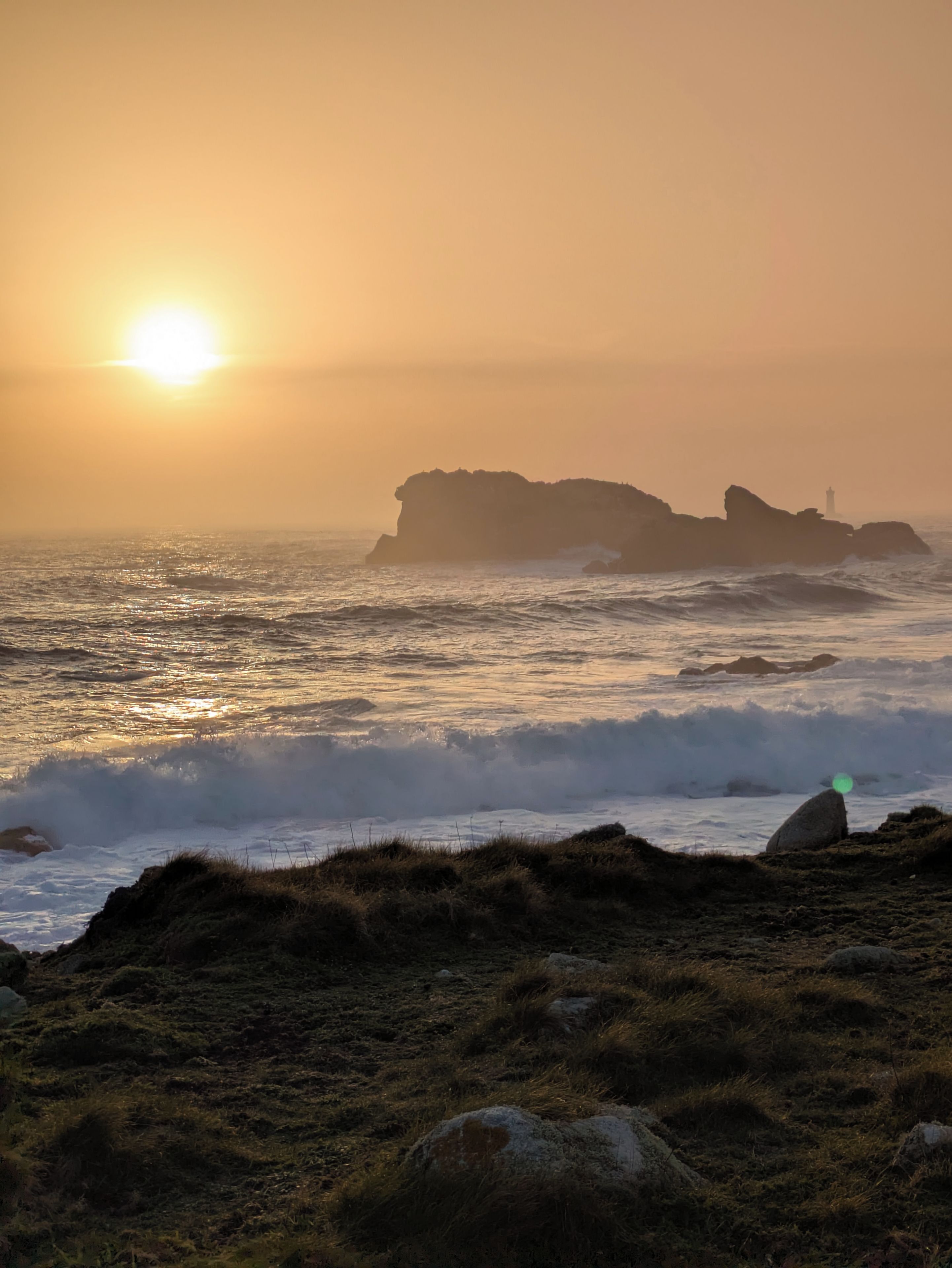 Un paysage côtier avec un promontoire rocheux et des vagues au coucher du soleil.
