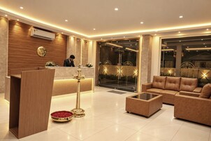 Un moderno vestíbulo de hotel con una recepción, un conjunto de sofás y una lámpara decorativa.