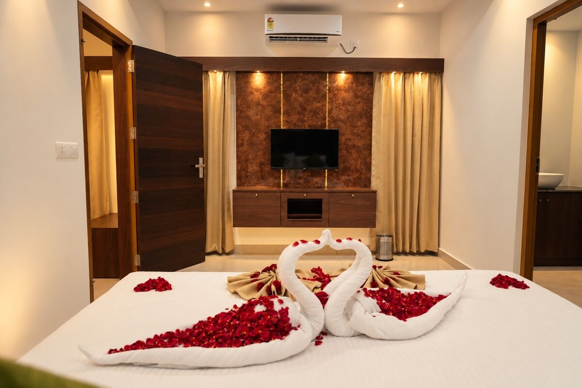 A hotel room with a bed, a television, a minibar, and a wall-mounted air conditioner.