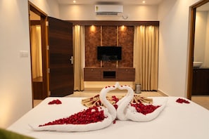 A hotel room with a bed, a television, a minibar, and a wall-mounted air conditioner.