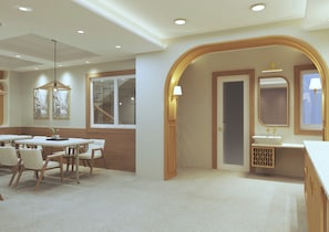 A hotel room with a dining area, a bathroom with a sink and mirror, and a staircase leading to an upper floor. - Aryan Inn Hotel (Varanasi)